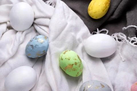 Easter eggs multicolored on the fabric. Easter background with eggs and feath Stock Photos