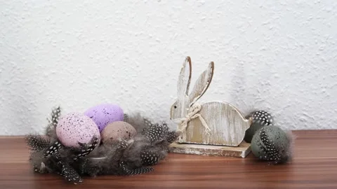 Easter eggs in the nest of feathers and wooden rabbit Stock Footage 234069026