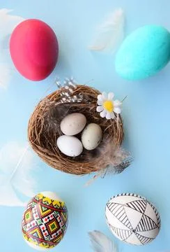 Easter Eggs in Nest with Feathers on Blue Background, Flat Lay Stock Photos