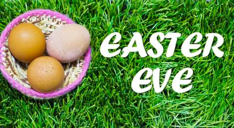 Easter eggs in nest on grass with text: Easter eve. Stock Photos