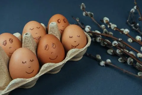 Easter eggs with painted funny faces in carton box and willow branches isolated Stock Photos