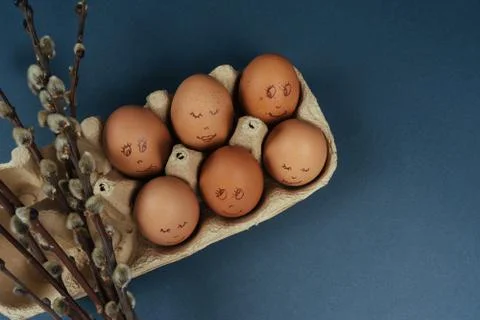 Easter eggs with painted funny faces in carton box and willow branches isolated Stock Photos
