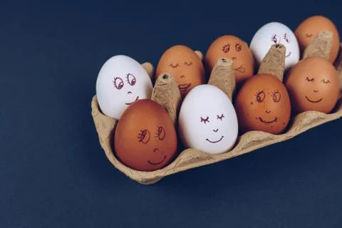 Easter eggs with painted funny faces in carton box isolated on dark background Stock Photos