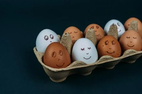 Easter eggs with painted funny faces in carton container box isolated on dark Stock Photos