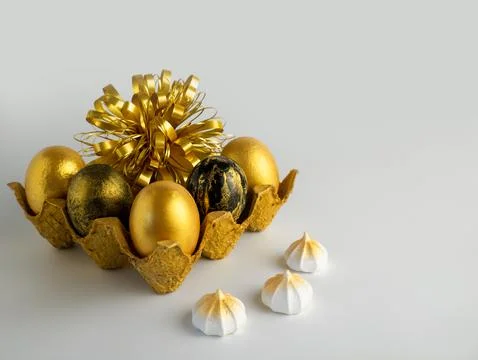 Easter eggs painted in gold and black in a textured stand on a white backgr.. Stock Photos