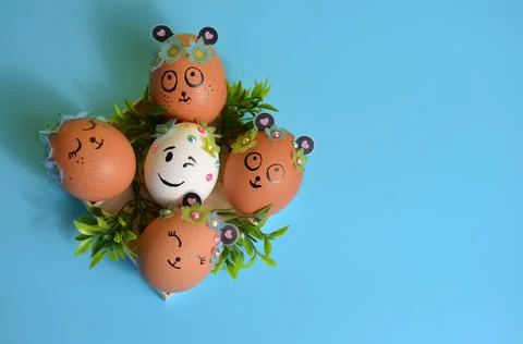 Easter eggs with painted muzzles on a blue background. Easter. Stock Photos