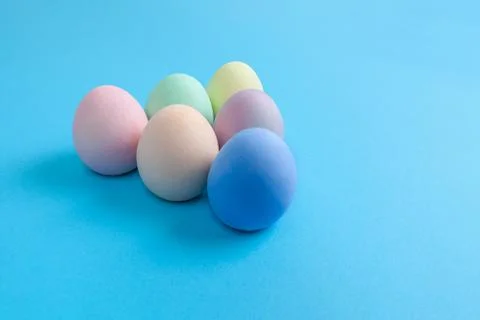 Easter Eggs painted in plain colors arranged in triangle shape on blue backgr Stock Photos