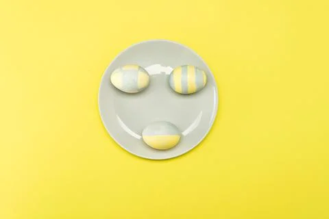 Easter eggs painted yellow-gray in a gray plate on a yellow background Stock Photos