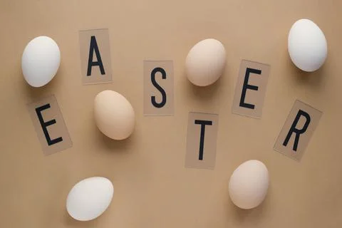 Easter eggs on pastel brown background with lettering. Top view. Flat lay. Mi Stock Photos
