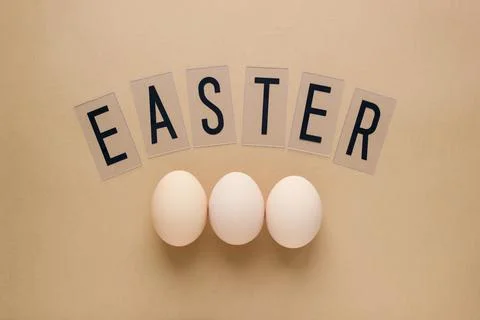 Easter eggs on pastel brown background with lettering. Top view. Flat lay. Mi Stock Photos