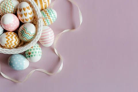 Easter eggs in pastel colors with a pattern in white basket on pink background. Stock Photos