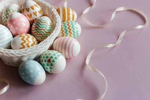 Easter eggs in pastel colors with a pattern in white basket on pink background. Stock Photos