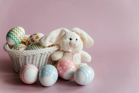 Easter eggs in pastel colors with a pattern and a white toy rabbit in a basket Stock Photos