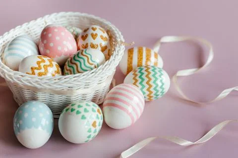 Easter eggs in pastel colors with a pattern in white basket on pink background. Stock Photos