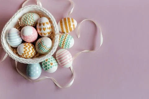 Easter eggs in pastel colors with a pattern in white basket on pink background. 스톡 사진