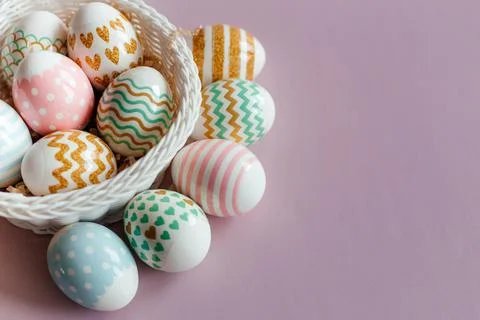 Easter eggs in pastel colors with a pattern in white basket on pink background. 스톡 사진
