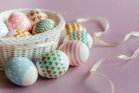 Easter eggs in pastel colors with a pattern in white basket on pink background. Stock Photos