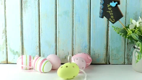 Easter eggs in pastel colors with silk ribbons and small flowers lie on a table Stock Footage 232856473