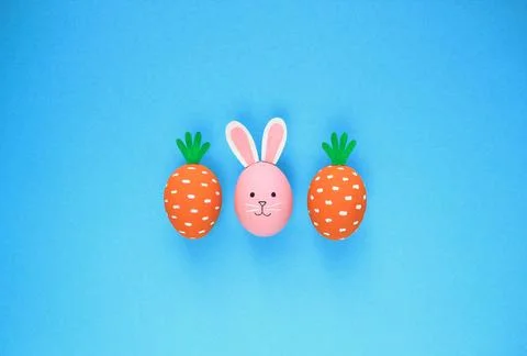 Easter eggs pattern made with painted carrots and bunny on blue background 스톡 사진