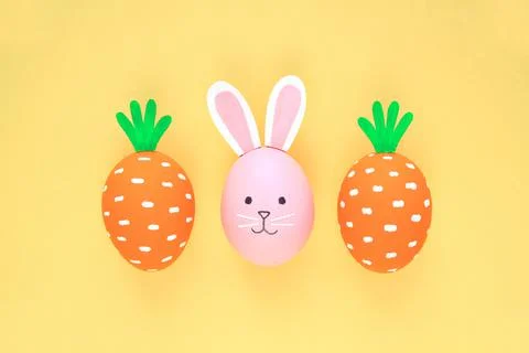 Easter eggs pattern made with painted carrots and bunny on yellow background 스톡 사진