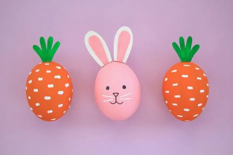 Easter eggs pattern made with painted carrots and bunny on violet background 스톡 사진