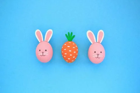 Easter eggs pattern made with painted carrot and bunnies on blue background Stock Photos