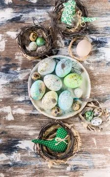 Easter eggs on a plate and in a small nest on colorful surface. Vertical shot Stock Photos