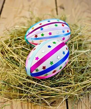 Easter eggs with ribbons and sequins in the hay Two easter eggs, decorated... 스톡 사진