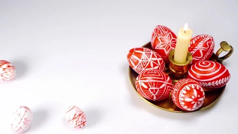 Easter eggs rolled up to candlestick and red eggs with folk white pattern Stock-Footage 127886840