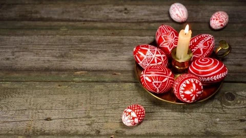 Easter eggs rolled up to candlestick with red eggs with folk white pattern Stock Footage 127887076