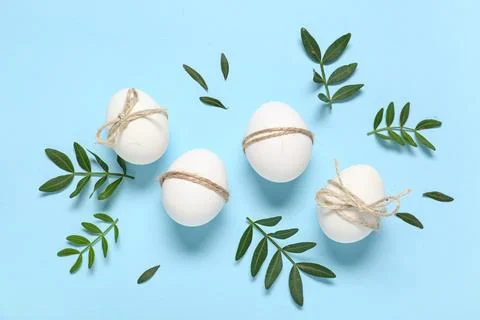 Easter eggs with rope and green leaves on blue background Stock Photos