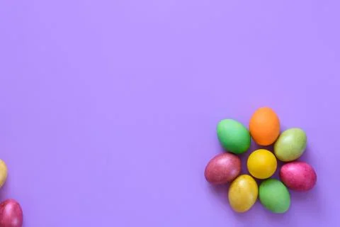 Easter eggs in the shape of a flower on a purple background, on the left ther Stock Photos