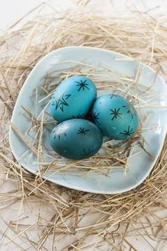 Easter eggs in straw plate on a white background 스톡 사진