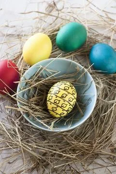 Easter eggs in straw plate on a white background Stock Photos