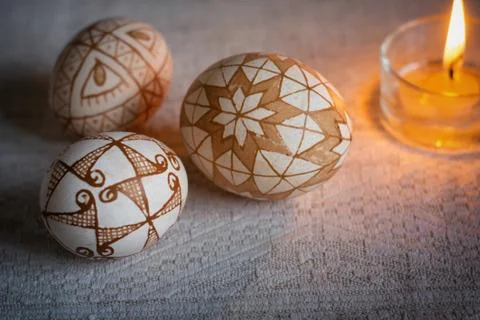 Easter eggs with traditional geometric patterns and a burning candle Stock Photos