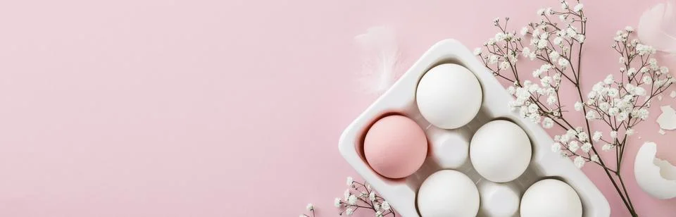 Easter eggs in white ceramic holder and flowers on pink background Stock Photos