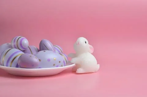 Easter eggs on a white plate and the Easter bunny. Purple background. Happy E Stock Photos