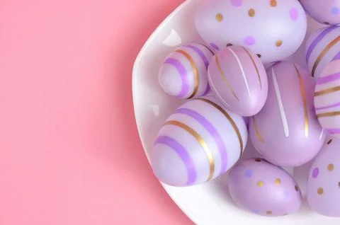 Easter eggs on a white plate close-up. Purple background. Happy Easter. Stock Photos