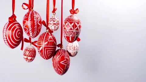 Easter eggs with white on red folk pattern, hang on red ribbons in left side Video stock 127887915