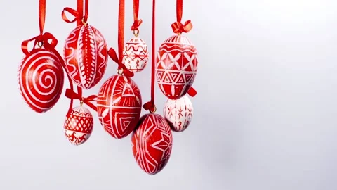 Easter eggs with white on red folk pattern, hang on red ribbons on right side Stock Footage 127887917