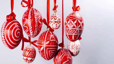 Easter eggs with white on red folk pattern, hang on red ribbons on left side Video stock 127887953