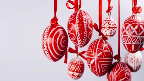 Easter eggs with white on red folk pattern, hang on red ribbons on right side Stock Footage 127887986