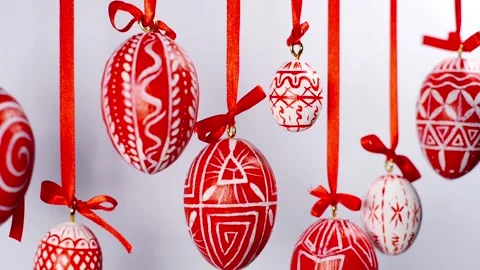 Easter eggs with white on red folk pattern, hang on red ribbons on white. Stock-Footage 127888163