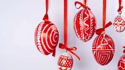 Easter eggs with white on red folk pattern, hang on red ribbons on right Stock-Footage 127888214