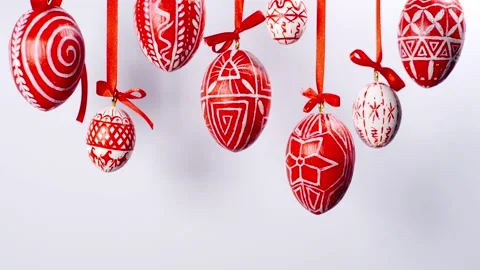 Easter eggs with white on red folk pattern, hang on red ribbons ontop side Stock Footage 127888230