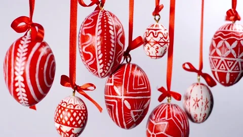 Easter eggs with white on red folk pattern, hang on red ribbons on white. Stock Footage 127888356