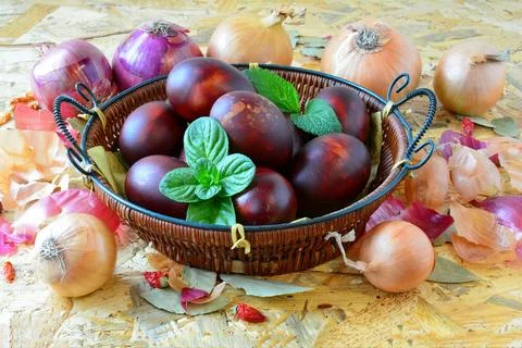 Easter eggs in wicker basket and yellow and red onion Stock Photos
