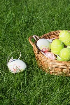 Easter eggs in wicker basket on green grass, spring holiday decoration Stock Photos