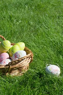 Easter eggs in wicker basket on green grass, spring holiday decoration Stock Photos