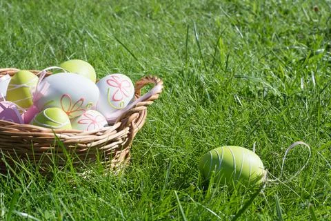 Easter eggs in wicker basket on green grass, spring holiday decoration Stock Photos